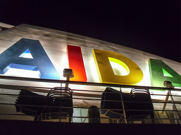 AIDAblu (AIDA Cruises) – beleuchtetes AIDA-Logo am Schornstein bei Nacht